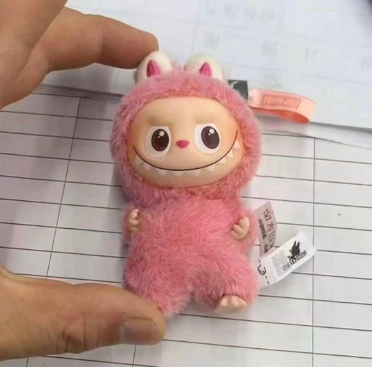 Small plush toy in a pink outfit held by a hand on a lined paper background