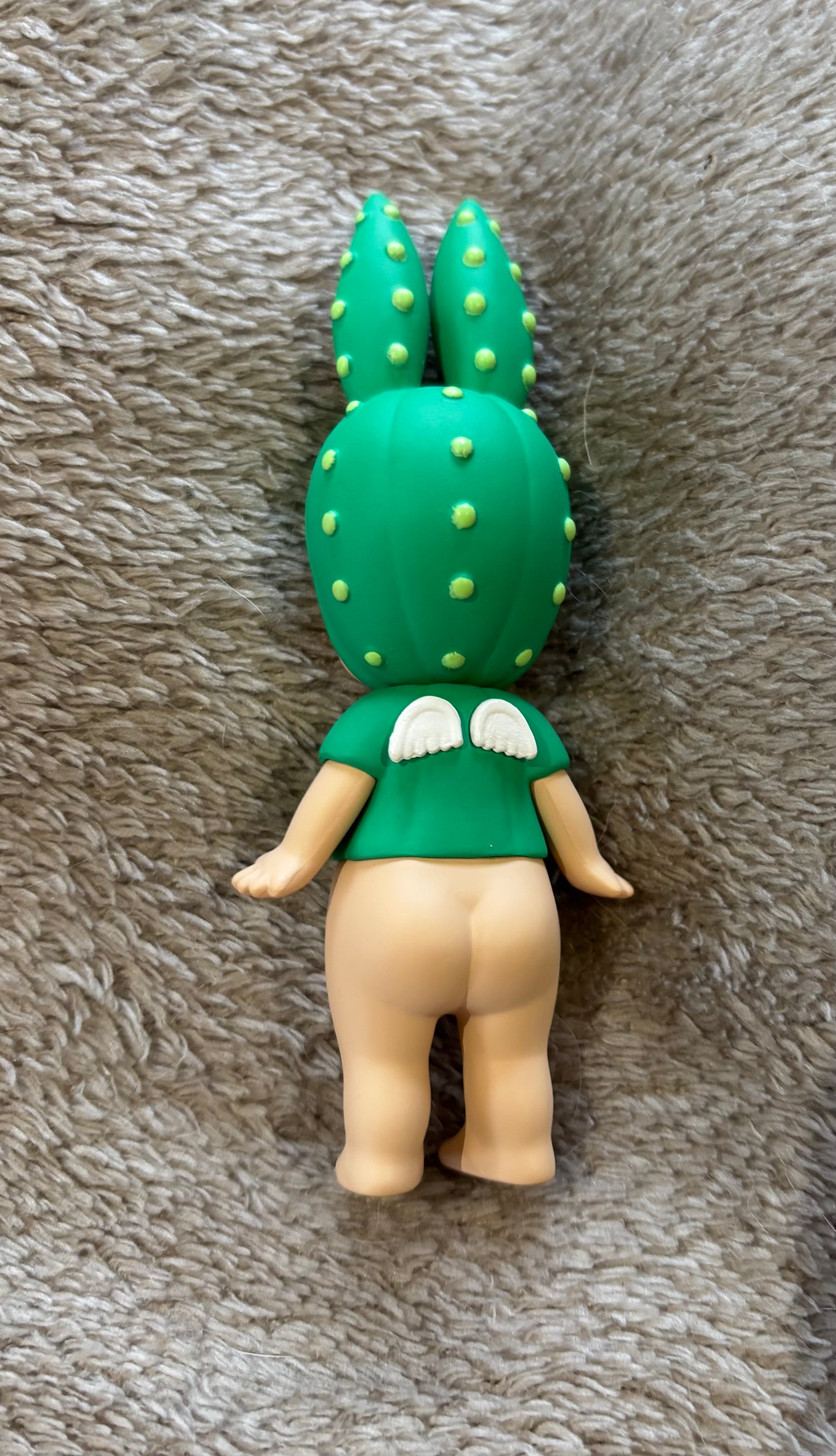 Toy figure with a green cactus head on a gray textured surface