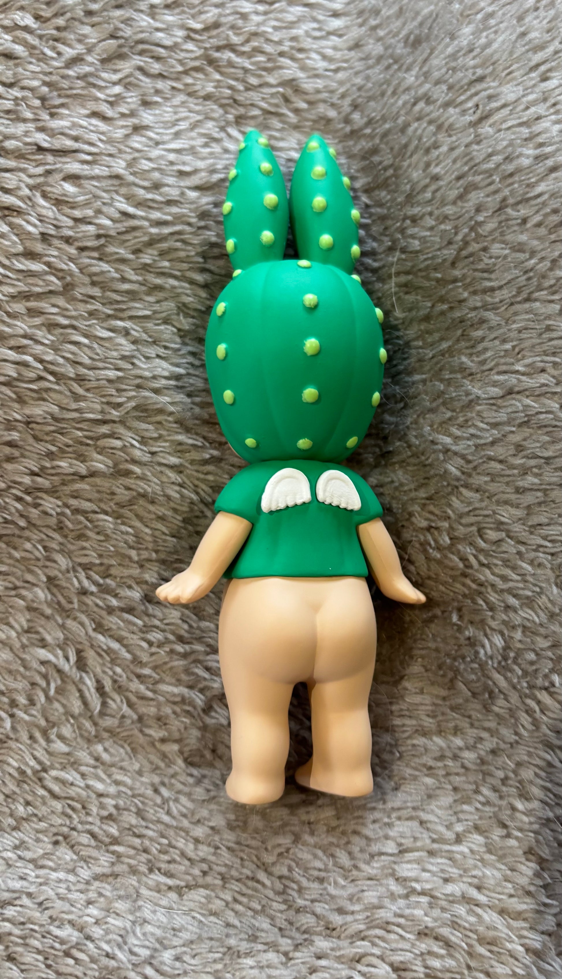 Toy figure with a green cactus head on a gray textured surface