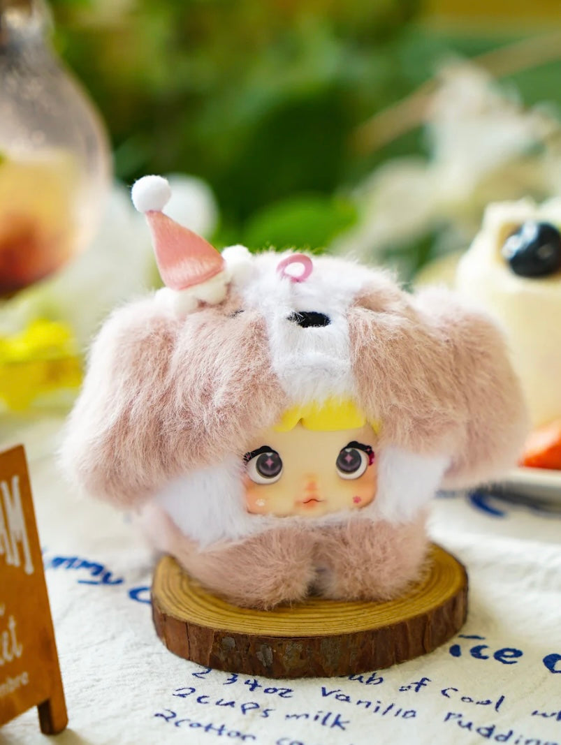 Plush nommi bag charm V1 toy with a character face on a wooden stand with a blurred background